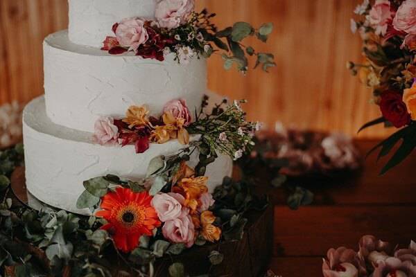 Bolo de festa decorado com fundo branco e flores de gérbera encanta a decoração da mesa