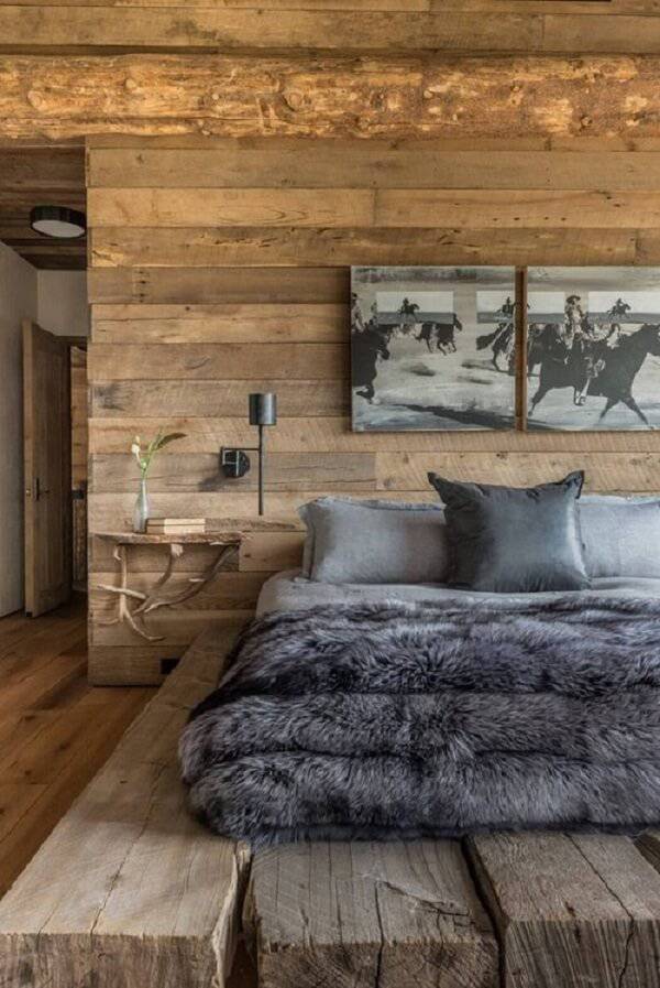 O quarto de casal rústico conta com parede e piso de madeira