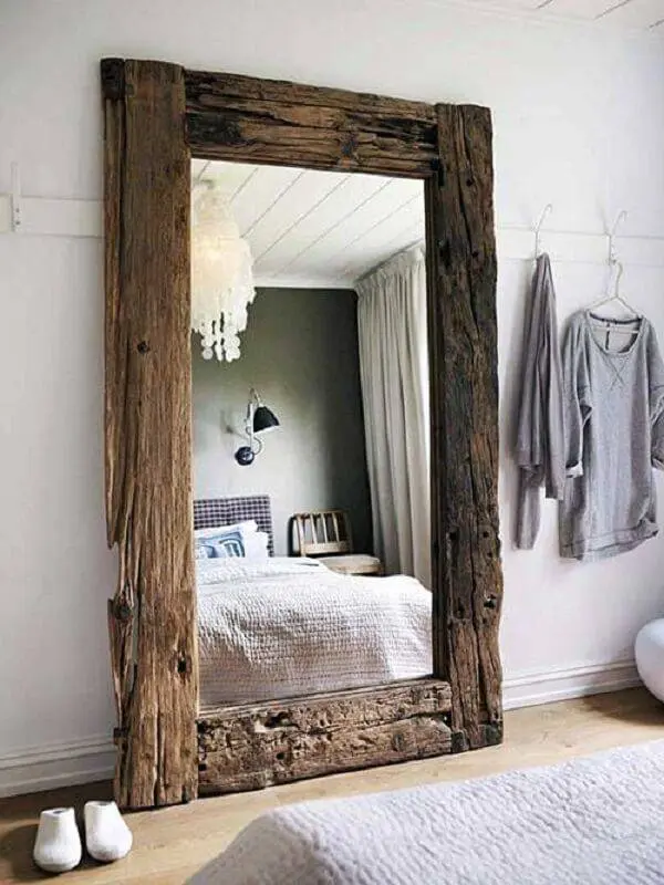 Espelho com moldura em madeira decora o quarto rústico