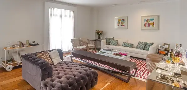 Sala de estar ampla com piso laminado flutuante e poltrona cinza com acabamento de capitonê