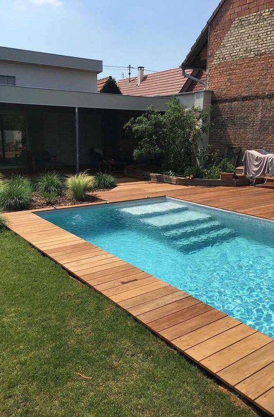 Borda de piscina alvenaria com madeira e gramado