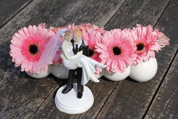 Decoração delicada de casamento com noivinhos e flores de gérbera rosa