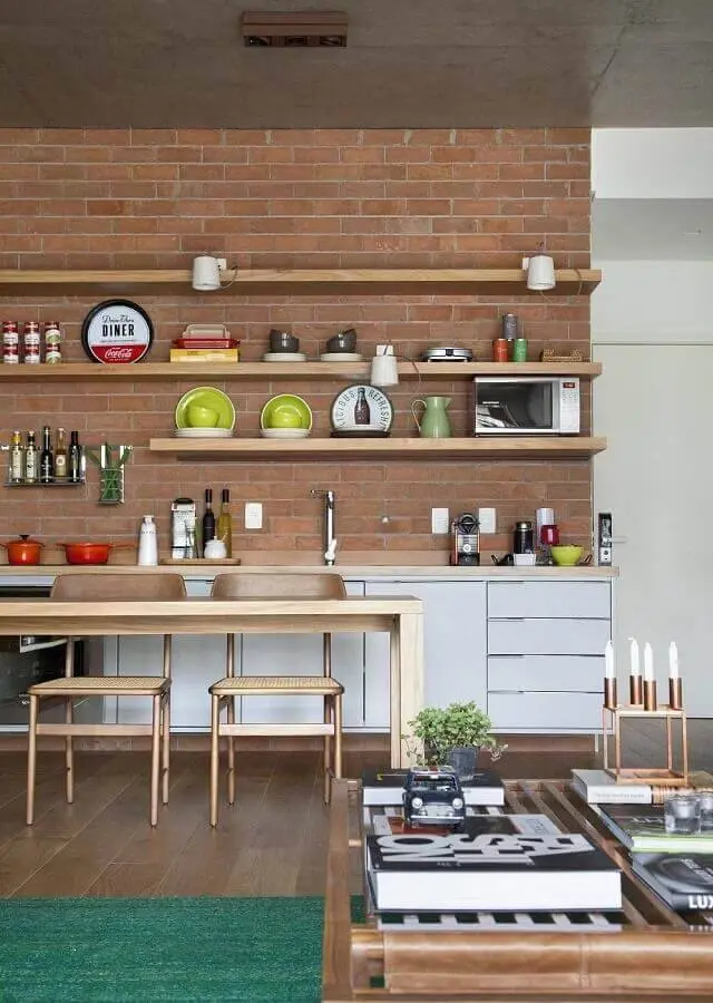 parede de tijolinho a vista com prateleiras de madeira para decoração de cozinha conceito aberto Foto Migs Arquitetura