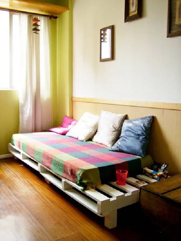 Sofá cama de pallet pintado de branco se harmoniza com a decoração do cômodo