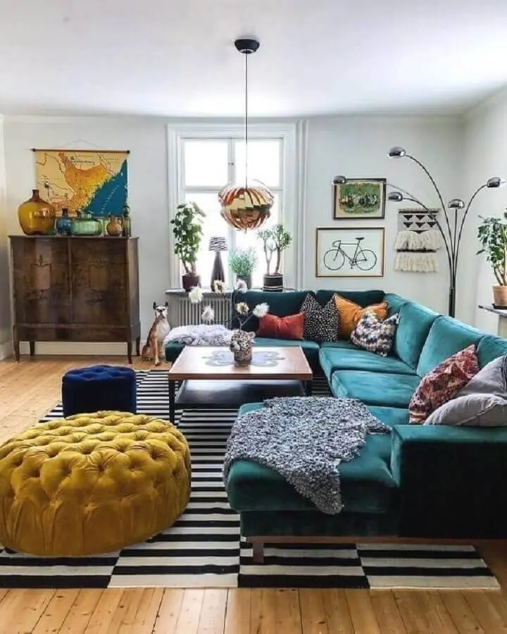 sala com sofá verde decorada com tapete preto e branco e puffs azul e amarelo Foto Ten is Extreme Shop