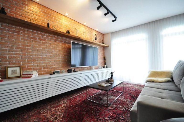 sala de estar decorada com parede de tijolo à vista e trilho de luz