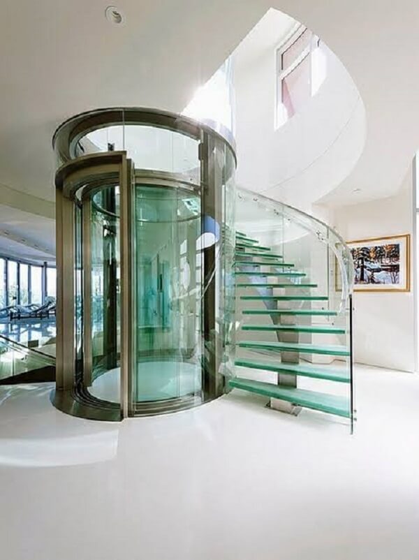 A escada de vidro segue o contorno do elevador