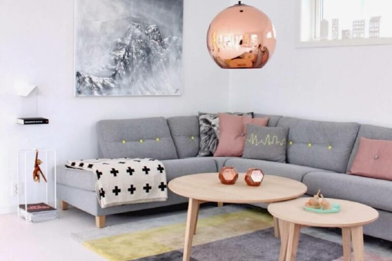 Decoração minimalista para sala de estar com sofá cinza de canto e pendente cobre redondo. Foto: We Heart It