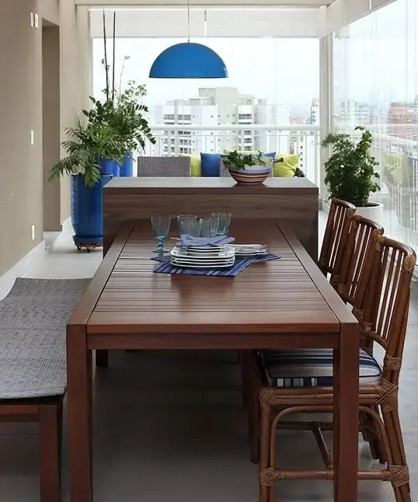 Mesa de jantar de madeira com cadeiras de estofado azul e luminária metálica