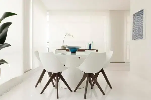 Mesa de jantar redonda branca se harmoniza com a decoração clean do ambiente