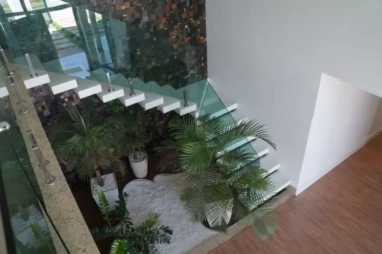 Monte um jardim de inverno em baixo da escada com guarda-corpo de vidro. Fonte: Carin Cordeiro Gonçalves