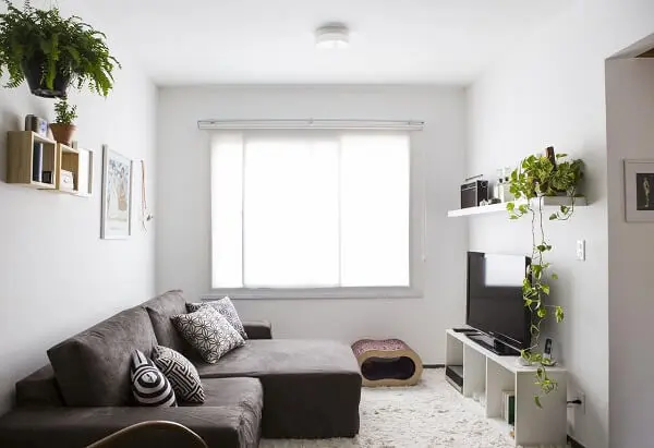 Sala com sofá de veludo marrom e tapete de pelinho branco