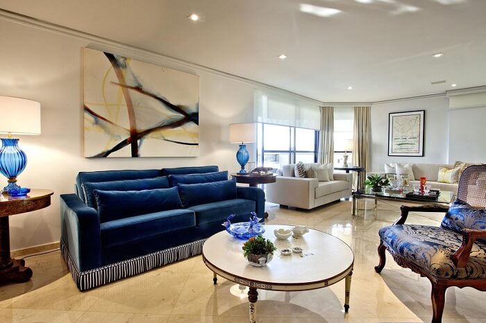 Sala de estar com sofá azul e quadros grandes para sala
