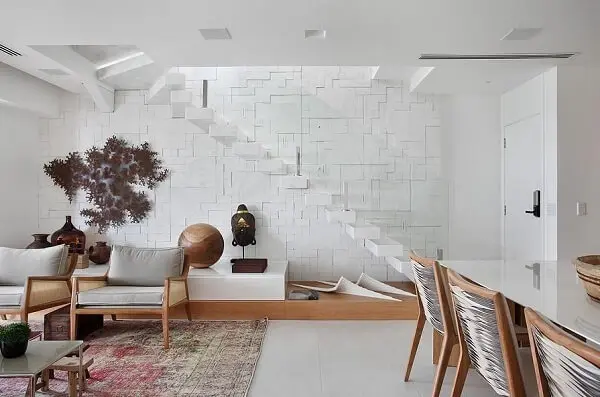 Sala de estar aconchegante com escada branca e guarda corpo de vidro