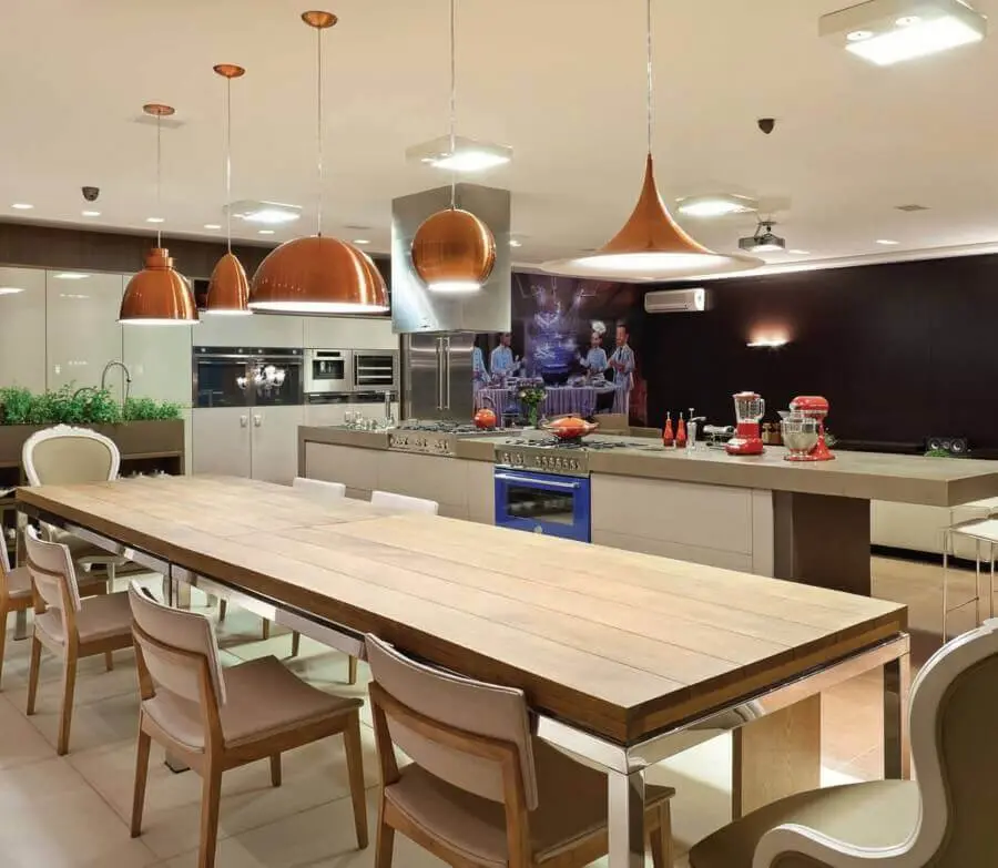 cozinha com sala de jantar integrada decorada com modelos diferentes de luminária pendente cobre Foto Anual Design
