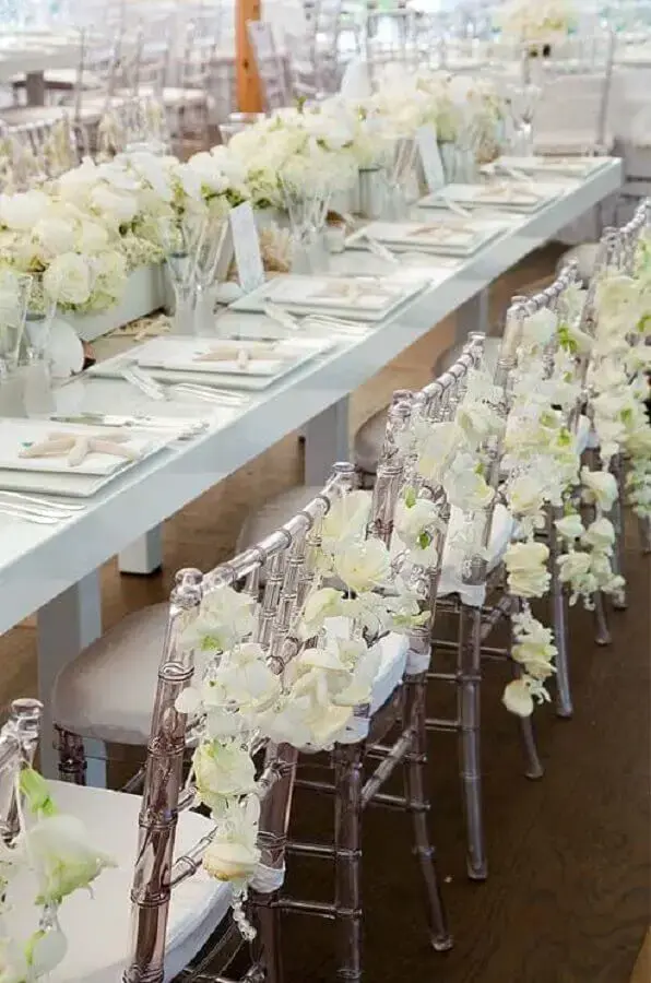 festa de aniversário de casamento decorada com arranjo de flores brancas e cadeiras de acrílico Foto Weddbook
