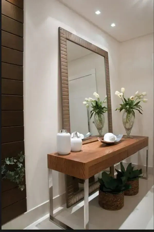 hall decorado com espelho de chão com moldura e aparador de madeira Foto Duca Móveis