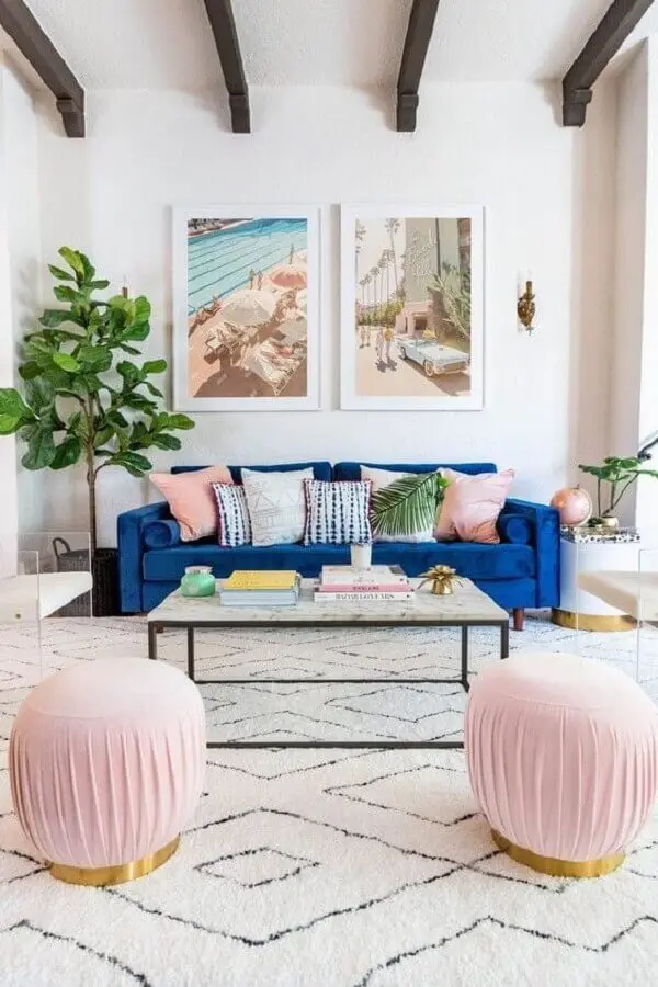 sala decorada com sofá azul de veludo e puff rosa redondo Foto Joss & Main
