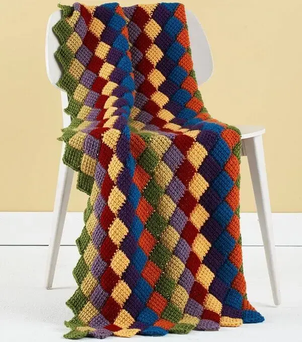 A manta colorida feita em crochê tunisiano traz descontração ao espaço