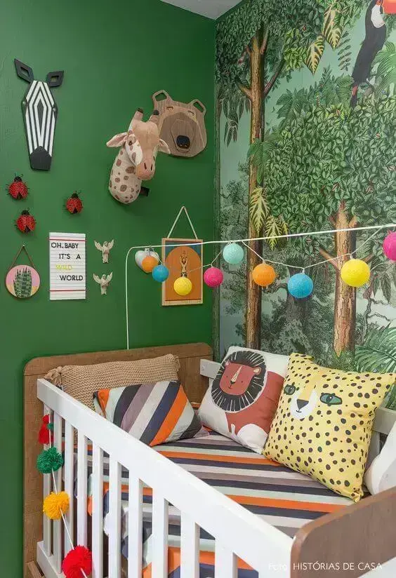 A parede verde do quarto de bebê realça a imagem das árvores na parede perpendicular - Fonte: Histórias de Casa