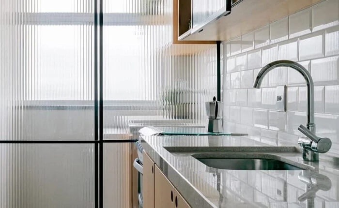 A porta de ferro com vidro canelado divide a lavanderia da cozinha