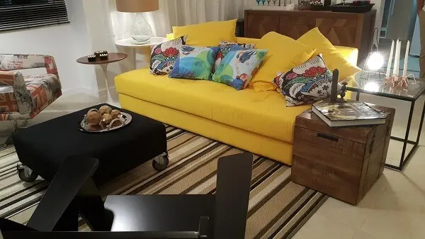 Sala com sofá amarelo e tapete listrado
