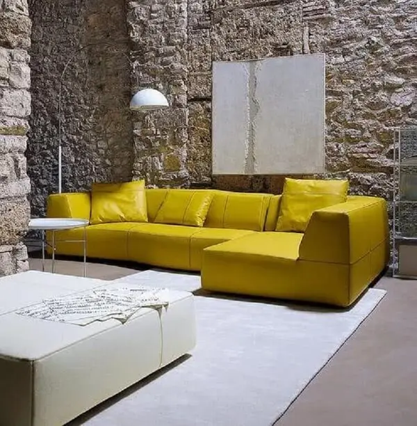 Sala de estar com parede de pedra e sofá de canto amarelo