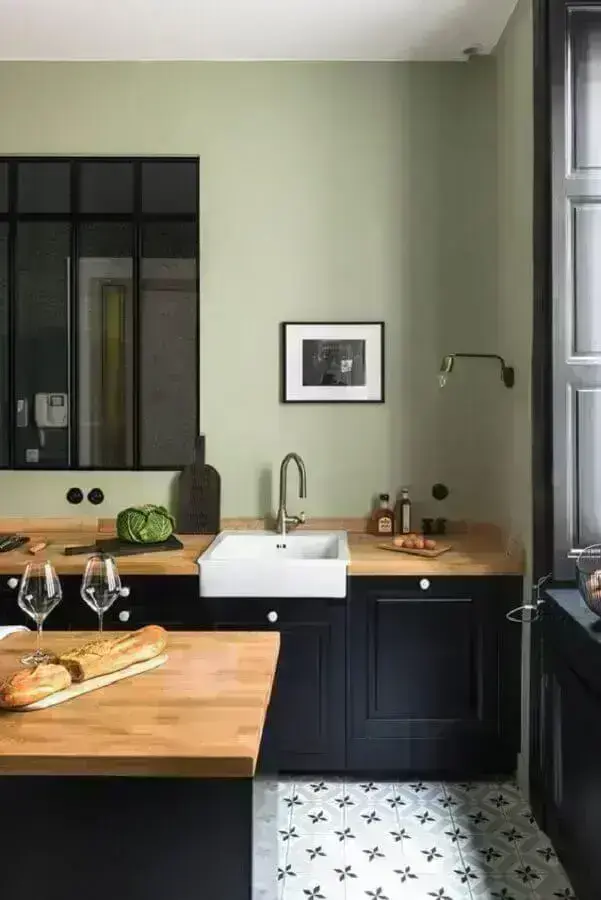 cozinha planejada com parede verde clara e armários pretos com bancada de madeira Foto House and Home