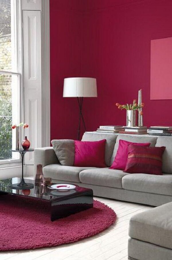 O tapete rosa pink redondo se harmoniza com as almofadas e paredes do ambiente