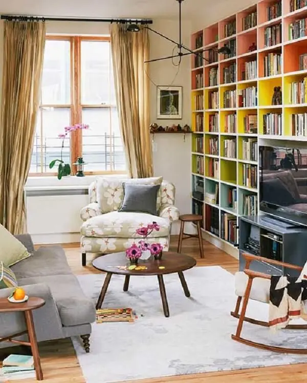 Sala de estar com estante nichos colorida acomoda diversos livros