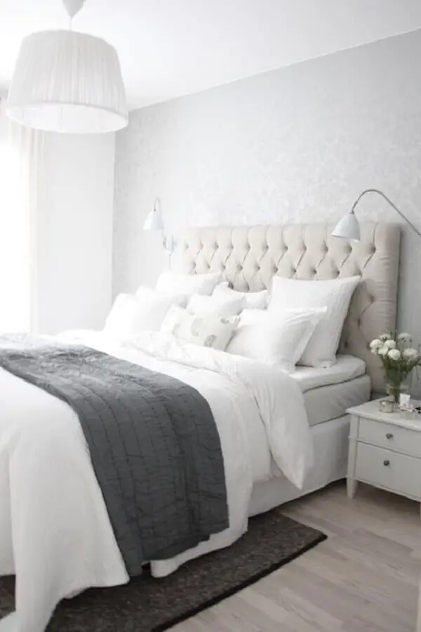 quarto branco decorado com cabeceira capitonê e papel de parede cinza claro Foto Sodimac