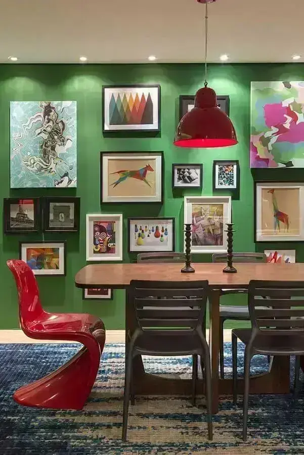 sala de jantar decorada com parede verde e vários quadros Foto Assetproject