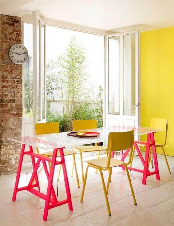 tons de amarelo para parede de sala de jantar decorada com mesa de tampo de vidro e base rosa Foto Webcomunica