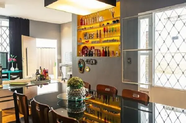 Os nichos coloridos na sala de jantar auxiliam na organização de taças e garrafas