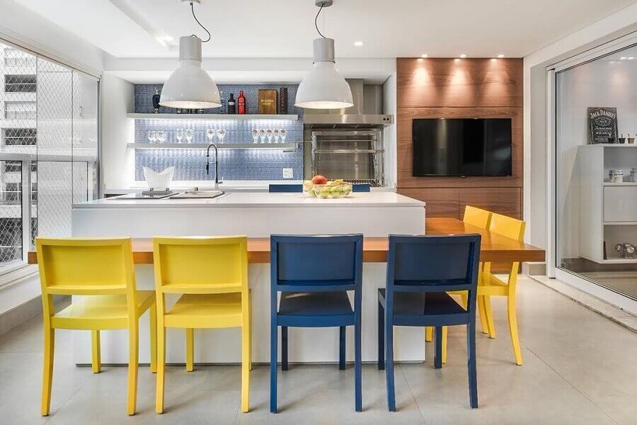varanda gourmet decorada com bancada de madeira e cadeiras amarelas e azuis Foto Fernanda Dabbur Arquitetura e Interiores