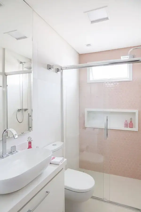 Banheiro rosa parede com revestimentos rosa e bancada branca 