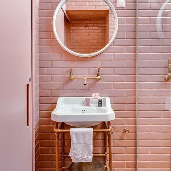 Banheiro rose gold espelho redondo e paredes de tijolos 