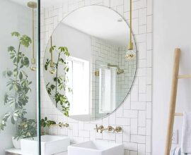 Decoração clean com espelho para banheiro redondo e gabinete suspenso de madeira. Foto: PURE Design Inc