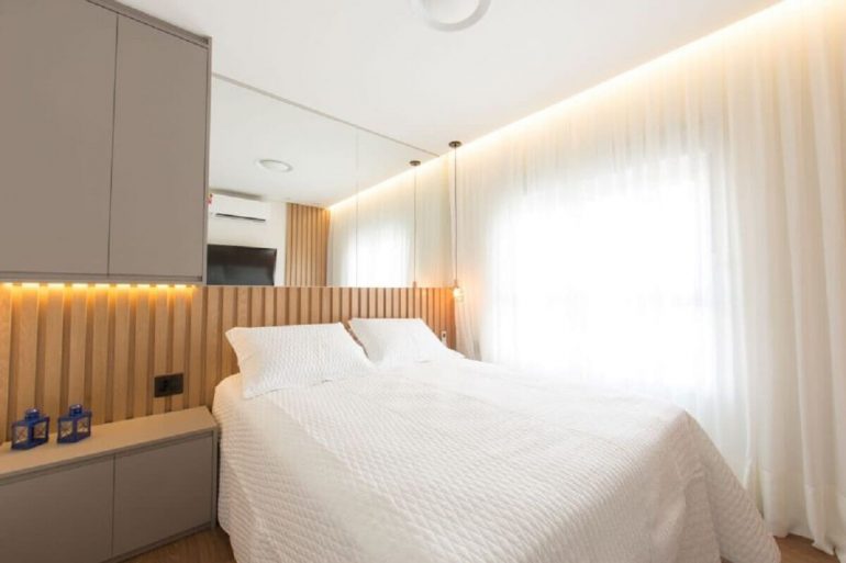 Decoração em cores neutras para quarto com cabeceira de madeira e pendente ao lado da cama