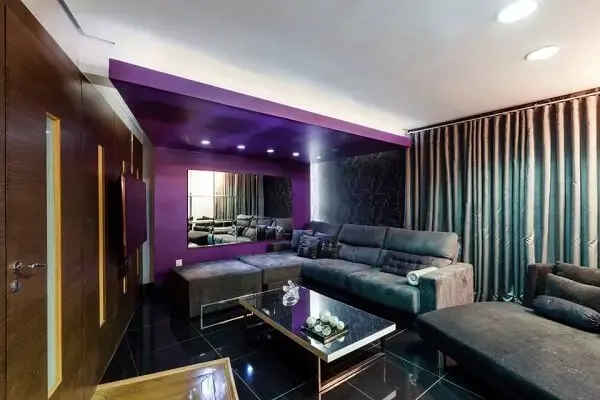 Decoração ousada para sala de tv moderna com parede roxa e cortina metalizada