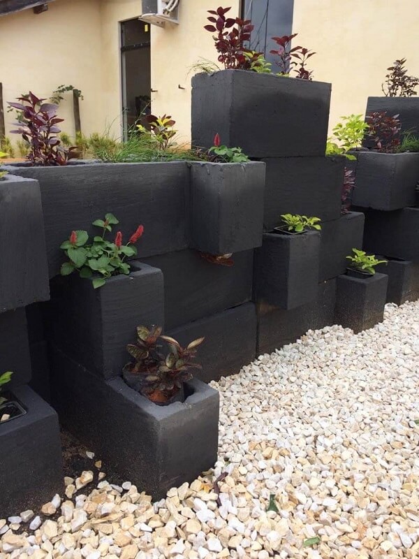 Blocos de concreto colorido de preto com flores e plantas