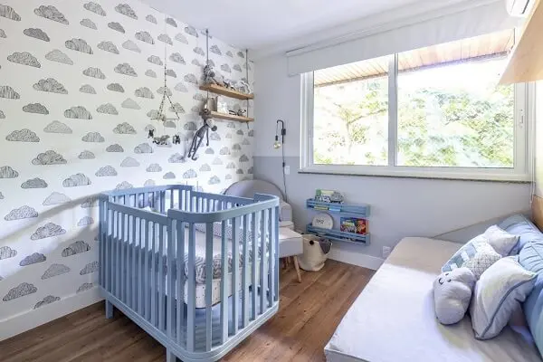 Quarto de bebê cinza com nuvens em papel de parede e berço azul 