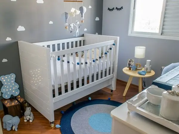 Quarto de bebê cinza e azul com detalhes em azul como luminária em formato de urso 