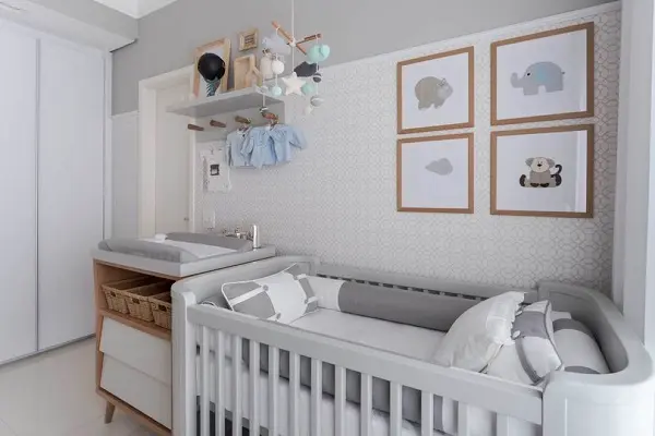Quarto de bebê cinza e branco com quadros na parede