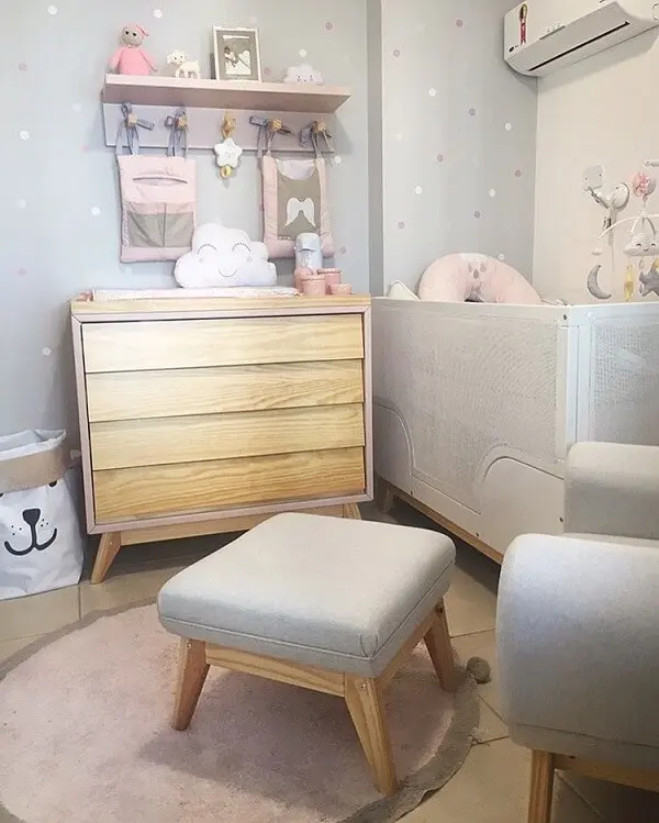 Quarto de bebê cinza e rosa com cômoda de madeira 