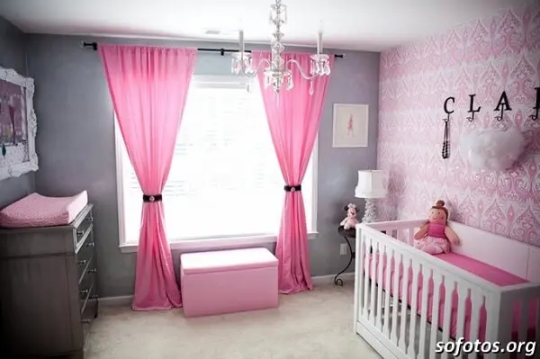 Quarto de bebê cinza e rosa com cortinas rosas e lustre