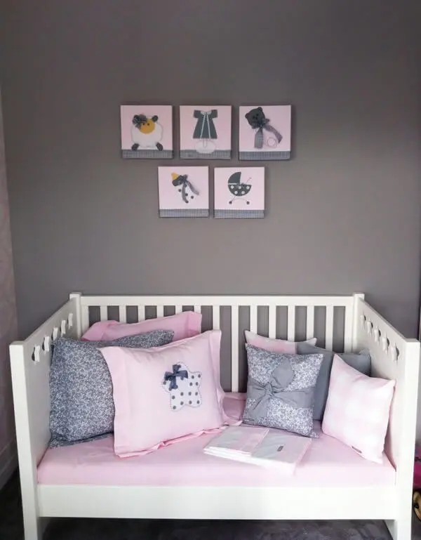 Quarto de bebê cinza e rosa com parede cinza escuro e quadros