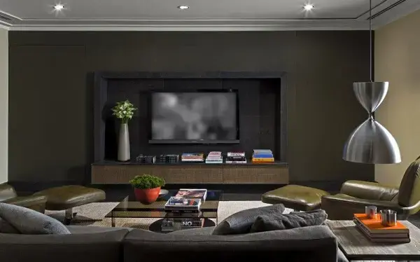 Sala de tv moderna com decoração escura e iluminação pontual