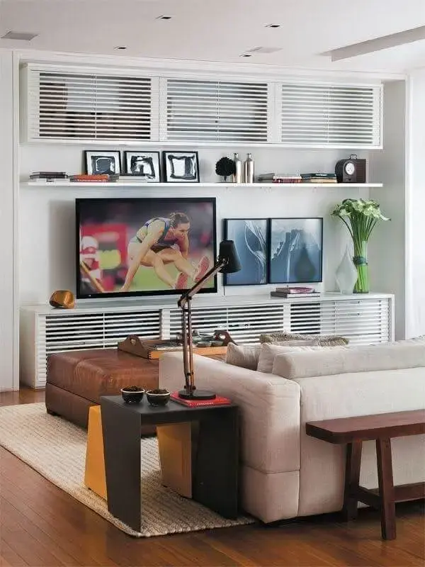 Sala de tv moderna com decoração clean e puff marrom no centro