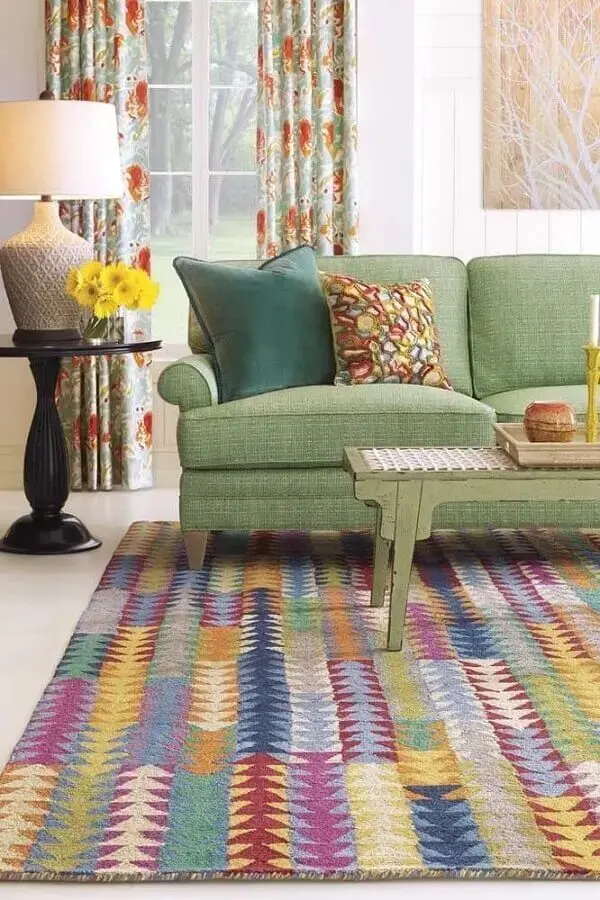Sofá verde e tapete de retalhos coloridos complementam a decoração da sala de estar